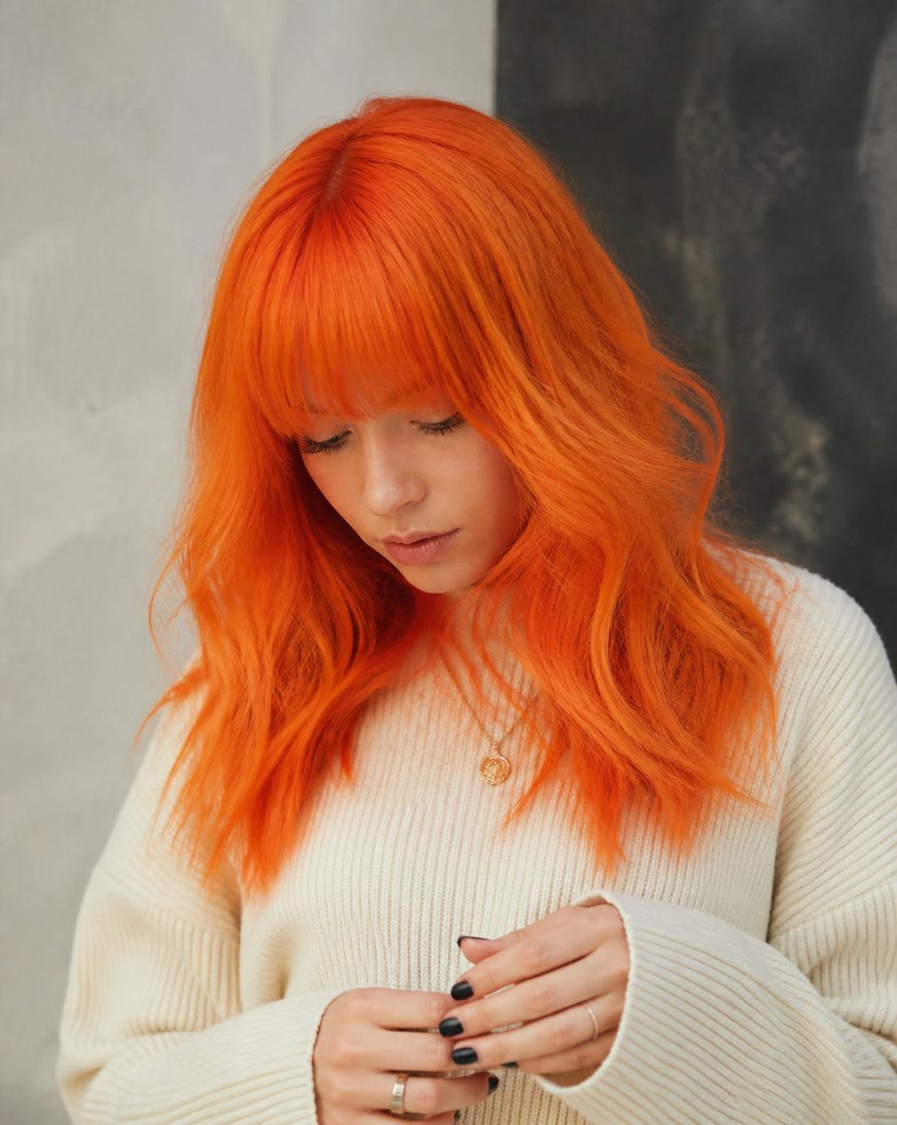 Model with vivid tangerine orange dyed hair and fringe